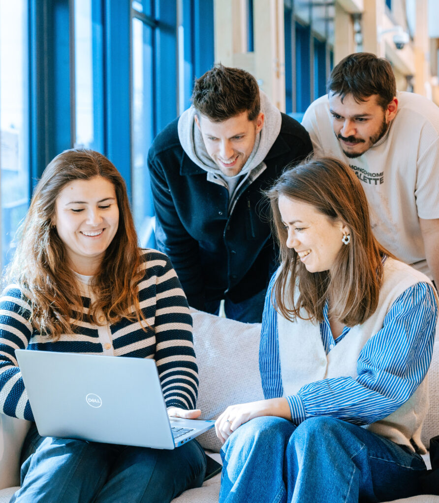 Team collaboration in a modern workspace at Voyage Privé, sharing ideas over a laptop.